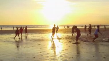 Kuta, Bali, Endonezya - 1 Mayıs 2017: futbol oynamak, ıslak kumsalda çıplak ayakla çalışan, güzel altın ışık günbatımında topu tekmeleme neşeli yerel çocuklar. Asya çocuk doğarken oyun