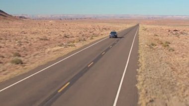 Hava: Utah flatlands, ABD bir boş yol yalak kumtaşı çölde boyunca bir siyah Suv araba yukarıda uçan. İnsanlar üzerinde yalak çöl manzara yerel otoyol güneşli günde seyahat yolculuğa.