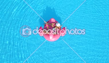 Hava üst aşağı genç çift toasting ve kokteyller yatan ise içerken Şişme flamingo floatie eğlenceli. Seksi çift içki yudumlarken ve üzerinde pembe flamingo havuzu su üzerinde yüzen rahatlatıcı mayo