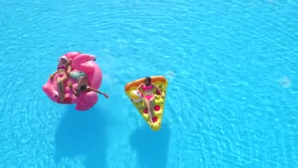 空中自上而下复制空间 身穿泳衣的男男女女躺在有趣的充气披萨上 火烈鸟漂浮在水面上 在游泳池里享用粉色火烈鸟和比萨饼的快乐朋友 — 图库视频影像