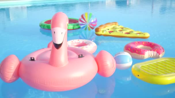 空的充气火烈鸟 比萨饼 甜甜圈和西瓜浮雕漂浮在池水 五颜六色的有趣枕头漂浮在水面上的空水池 — 图库视频影像