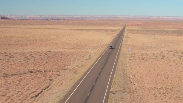 在犹他州犹他州平原的一条空旷的公路上飞行 在一辆黑色的 Suv 汽车上飞行 在阳光明媚的日子里 人们在当地高速公路上穿越沙漠景观 — 图库视频影像