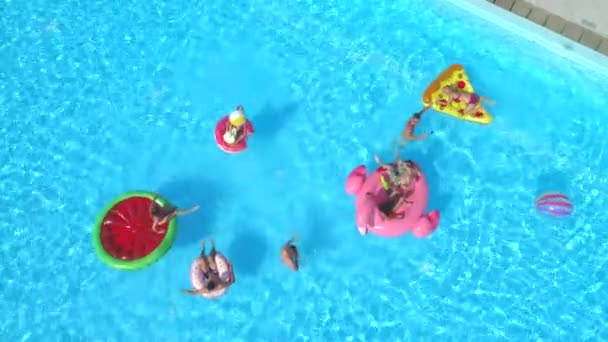 水を持つ陽気な友人は プール パーティーでカラフルな Floaties で戦います 遊び心のある男と女はね水とインフレータブルのピザ ドーナツ フラミンゴ スイカの山車の撮影 Selfies — ストック動画