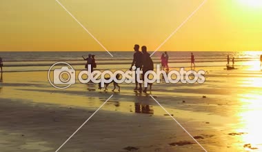 Kuta, Bali, Endonezya - 1 Mayıs 2017: turist keşfetmek muhteşem Bali Kuta Beach Altın ışık günbatımında kalabalık. Selfies alarak çiftler, arkadaş köpek, çocuklar oynarken, yürüyüş zevk sahil insanlar.