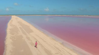 Hava: tanınmayan genç kız pitoresk kıyı manzara ve güzel pembe tuz buharlaşma havuz sıcak güneşli Meksika'da izlerken yükseltilmiş kumlu banka yürürken yaz tatillerini üzerinde uçan