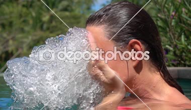 Ağır çekim, Close Up: Güzel ve genç birbayan spa su yüzünde yüzme havuzunda. Cennet Adası Bali tropikal ormanda açık lüks tatil yüz yıkama ıslak saçlı kız