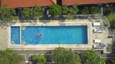 Hava aşağı üst: yenileme ve sıcak güneşli günde açık havuzu suda yüzen yaz tatilde tanınmaz halde kadın. Kız pembe bikini lüks yüksek sınıf Resort boş havuzda zevk