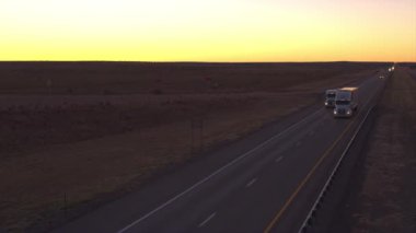 Hava yakın: otomobil ve navlun yarı kamyon yüklü mal meşgul karayolu boyunca sürüş ile şafakta kargo taşıma. Konteyner kamyon teslim taşıyıcı kargo altın günbatımında çekme.