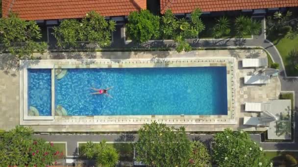 空中ダウン トップ 夏休みリフレッシュしのホット晴れた日の明確なプールで水泳に認識できない女性 贅沢な高級リゾートで空のプールで水泳を楽しんでいるピンクのビキニの女の子 — ストック動画