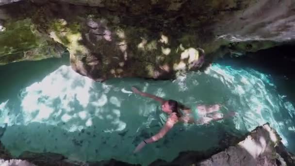 近くで何が起きているのでしょうか メキシコの有名なグランド センテ洞窟への岩の通路を通って 美しいクリスタル クリア リバーで泳ぐビキニ姿の若い女性 晴れた夏の日の地下水での女性の入浴 — ストック動画