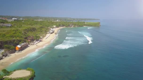 镜头耀斑 飞越梦幻般的白色沙滩 Balangan 海滩上阳光明媚的热带岛屿巴厘岛 游客游泳 人们日光浴 冲浪者捕捉泡沫波和享受假期在天堂 — 图库视频影像