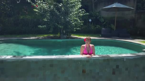 空中关闭远处微笑的年轻女子享受暑假在豪华旅游胜地在惊人的水稻梯田在阳光明媚的巴厘岛 女孩在无限水池观看棕榈丛林在热带海岛 — 图库视频影像
