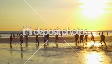 Kuta, Bali, Endonezya - 1 Mayıs 2017: futbol oynamak, ıslak kumsalda çıplak ayakla çalışan, güzel altın ışık günbatımında topu tekmeleme neşeli yerel çocuklar. Asya çocuk doğarken oyun