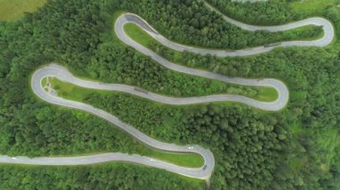 Anteni, üst aşağı: Motosiklet ve araba zig zag dolambaçlı yol dağ yamacında yemyeşil yoğun çam ormanı üzerinde sürüş. Ormanın içinden kıvrıla kıvrıla Curvy kıvrımı karayolu saç tokası ile döner