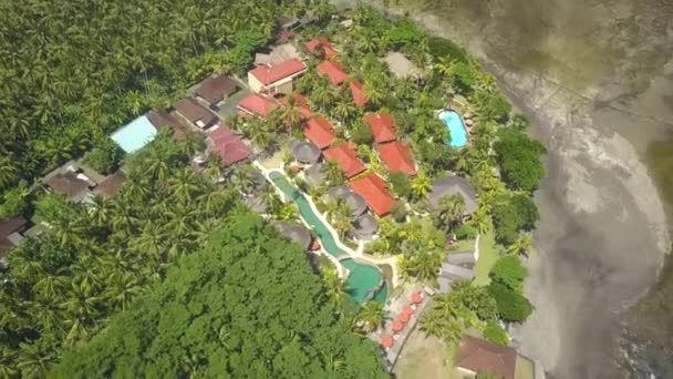 トップダウン 美しいヴィラ 休日のバンガロー Oceanfornt 休暇の家 日当たりの良いバリ島の楽園での豪華な海岸の緑豊かなヤシの木ジャングルに高級観光リゾートのプール — ストック動画
