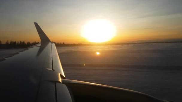 在金色的淡淡黄昏下 在终点机场 从喷气式客机窗口外眺望飞机机翼和绚丽的雪景 冬季假期的人们在日出时乘飞机抵达芬兰 — 图库视频影像