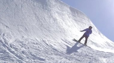 Ağır çekim: büyük dağ kar Park'ta yarım boru sürme, yüksek halfpipe duvardan atlama, hile ve rotasyonlar kapmak ile güneşli kışın gerçekleştirme genç pro snowboarder