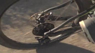 Yakın: hızlı, tanınmaz halde erkekler güneşli doğada bisikleti pedal iplik dağ bisiklet lastiği. Çakıl yol boyunca bisiklet dağ bisikletçinin
