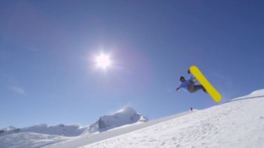 Ağır çekim: büyük dağ kar Park'ta yarım boru sürme, yüksek halfpipe duvardan atlama, hile ve rotasyonlar kapmak ile güneşli kışın gerçekleştirme genç pro snowboarder