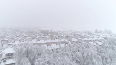 Hava: Kış gününde taze karla kaplı çatıları ile sessiz banliyö kasabası üzerinde uçan. Karlı kış gününde pastoral sıra evler. Huzurlu banliyösünde banliyö çatıları ve karlı arka bahçeleri üzerinde Uçan.