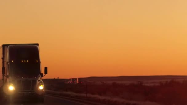特写镜头耀斑 半卡车驾驶和运输货物在空公路横跨大平原在黄金早晨 货运卡车运输货物在州际高速公路在令人惊叹的日落 — 图库视频影像