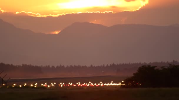 赤と白の安全ライトは 夜明けに絵のように美しい山岳地帯の空港で輝きと照明空の滑走路を照らします エアロドロームピストフィールドの指向性交通信号と標識が輝く — ストック動画