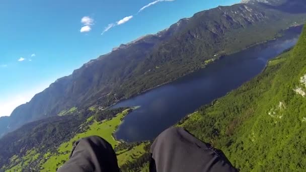 POV: δίδυμο αλεξίπτωτο πλαγιάς που πετούν πάνω από την πανέμορφη καταπράσινη ορεινή κοιλάδα και τη γαλάζια λίμνη — Αρχείο Βίντεο