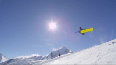 Ağır çekim: büyük dağ kar Park'ta yarım boru sürme, yüksek halfpipe duvardan atlama, hile ve rotasyonlar kapmak ile güneşli kışın gerçekleştirme genç pro snowboarder