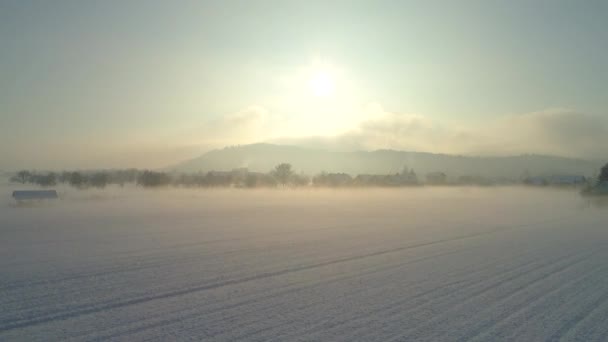 Luftaufnahme Flug Über Neblige Schneefelder Vor Einer Kleinen Vorstadt Silhouette — Stockvideo