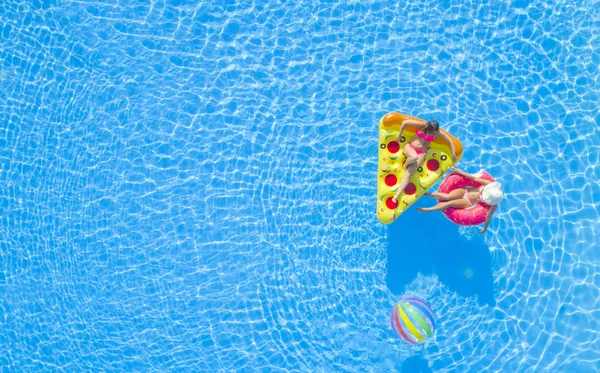 空中トップダウン水の上に楽しいインフレータブルピザとフラミンゴ浮動ラウンジャーに横たわってピンクビキニ水着でリラックスした女の子 夏休みのガールフレンドは スイミングプールでカラフルな浮遊を楽しんで — ストック写真