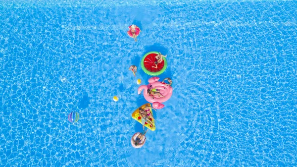 陽気な幸せな友人は 夏のプールパーティーでカラフルな浮遊物で水銃の戦いをしています Playful Guys Girls Splashing Water Inflatable Pizza Doughnut — ストック写真