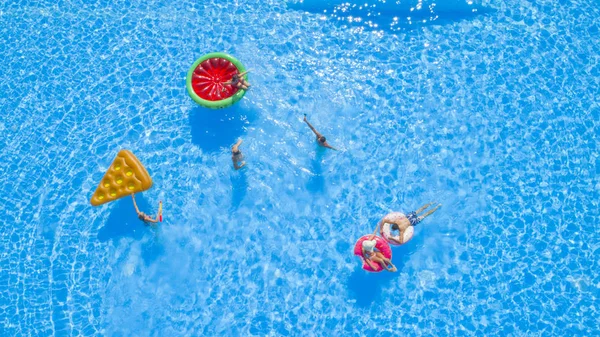 航空写真 陽気な夏のプールでカラフルな Floaties を楽しんでパーティーします 遊び心のある男と女はね水とインフレータブルのピザ ドーナツ フラミンゴ スイカの山車の撮影 Selfies — ストック写真
