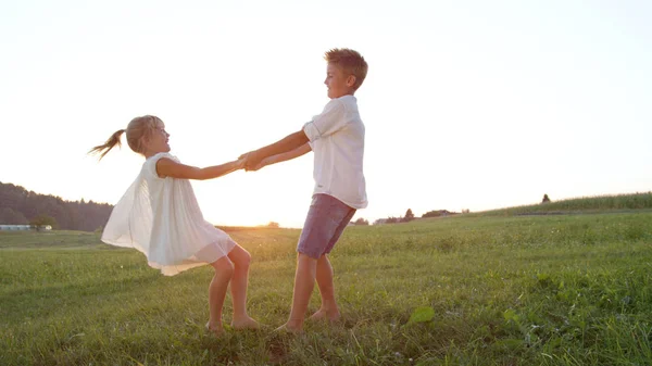 Lense Flare Dos Niños Pequeños Tomados Mano Bailando Descalzos Prado — Foto de Stock