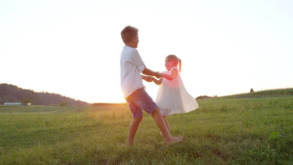 Lense Flare Dwoje Małych Dzieci Trzymając Się Ręce Tańczy Się — Zdjęcie stockowe