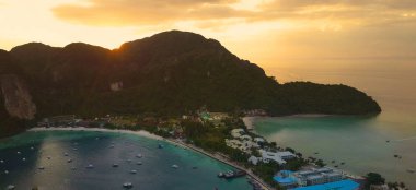 Hava: Phi Phi Islands teknelerin tam kalabalık plaj sahil yakınında demir attı. Sakin zümrüt koyu ve büyük uçurum arkasında güneş ayar pastoral yaz akşam manzara çok sayıda tekne demirlemiş.