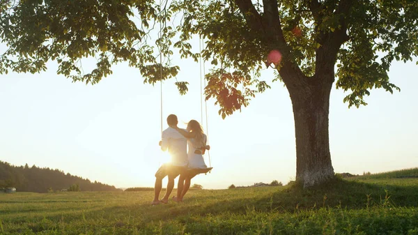 Lens Flare Silhouette Charmant Jeune Couple Assis Sur Corde Balançant — Photo