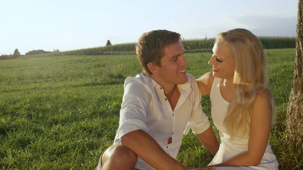 一对美丽的夫妇在爱在阳光明媚的草地上拥抱和亲吻 男孩和女孩享受他们的浪漫约会在农村 新婚夫妇互相注视着一个吻 — 图库照片