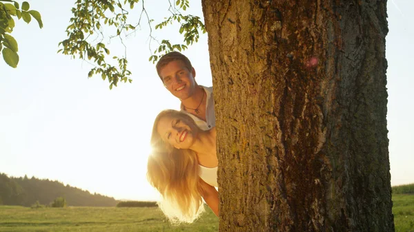 Close Lense Flare Smiling Couple Peeking Tree Summer Evening Sunrays — Stock Photo, Image