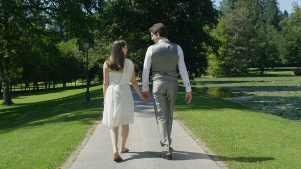 クローズアップ 幸せな妊娠中のカップルは 手を保持し 晴れた春にトラフグリーンパークを歩きます 妊娠中に妻と散歩をしている愛する男 結婚式の後に赤ちゃんを期待する若い新婚夫婦 — ストック写真