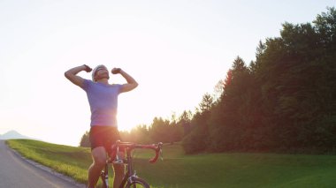 Mercek Parlaması, kopya alanı: Atletik sporcu güneşli yol bisiklet deneme başarılı bitiş kutluyor. Pro beyaz yol motorcu doğal yaz manzara karşısında zorlu eğitim yarışı bitirmek mutlu.