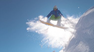 Yakın: Snowboarder toz karda kış günü güneşli dağlarda atlama. Aşırı freerider backcountry snowboard taze kar üzerinde parlak kış güneşi havadaki yüksek atlama sırasında spreyler.