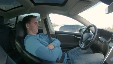 Beyaz adam kendini direksiyon araba sürücü koltuğuna otoyol trafik sıkışıklığı sırasında reclines. Uykulu adam geri eğilir ve autopiloted elektrikli arabada uykuya dalıyor. Korku veren özerk araba sürücüleri adam