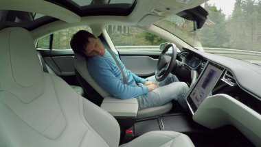 Tesla özerk, Şubat 2017: özerk bir elektrikli Tesla araba kendi kendine sürüş direksiyon direksiyonuna uyuyan erkek pilotu. Adam kırsal yol boyunca sürüş sırasında derin uykuya daldı