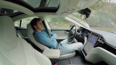 Tesla özerk Araba, Mart 2018:Male sürücü özerk bir elektrik Tesla araba kendi kendine sürüş direksiyon simidi yatıyor. Adam kırsal yol boyunca sürüş sırasında derin uykuya daldı