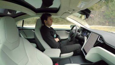Graz, Avusturya - 2 Şubat 2017: İşadamı yeni lüks özerk kendi kendine sürüş otomatik pilot Tesla Model S sürücüsüz araç içinde seyahat iş gezisinde. Elektrikli araç karayolu üzerinde kendisi tarafından sürüş