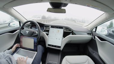 Tesla özerk araba-Şubat 4, 2017: lüks Tesla Model S özerk elektrikli araba otoyolda sürüş sabah kendi kendine otomatik. Tanınmayan işadamı seyahat ederken dizüstü bilgisayarda çalışma