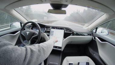 TESLA AUTONOMOUS CAR- FEBRUARY 4, 2017: Tesla autopilot self-driving in severe weather condition with no human intervention. Driver browsing the internet using touchscreen in futuristic autonomous car clipart