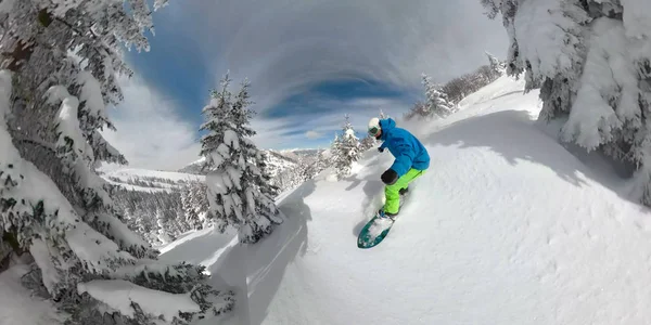 Extreme freeride snowboarder carving down the snowy mountain slope in sunny winter. Young man snowboarding fresh powder snow on sunny winter vacations in snowy mountains. Winter sports on sunny day