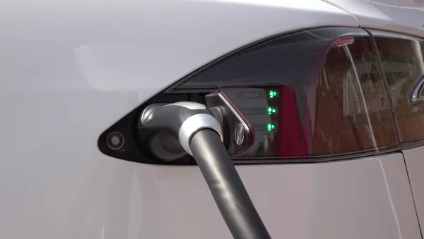 豪华特斯拉电动汽车的充电电池在增压站 昂贵的白色电动汽车充电 环保意识的交通工具插入加气 — 图库照片