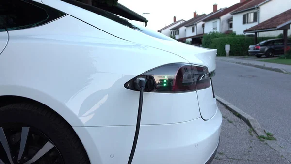 豪华特斯拉电动汽车的充电电池在家里院子里 昂贵的白色电动汽车充电 环保意识的交通工具插入加气 — 图库照片